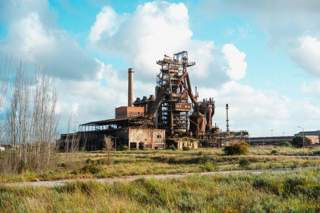 An abandoned factory amid a grassy landscape, showcasing industrial decay.