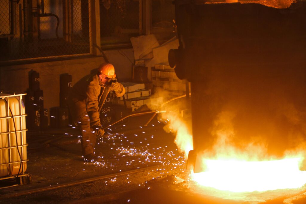 A steelworker in a factory welding near molten metal, showcasing industrial hard work.